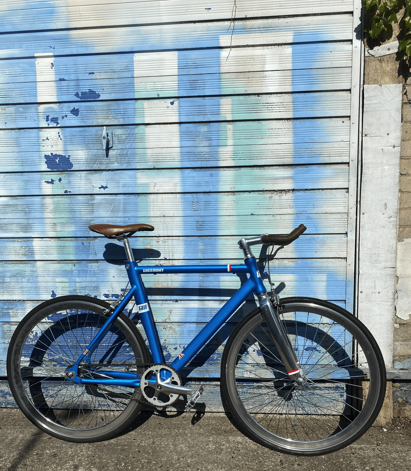 A blue bike in front of a blue garage door.