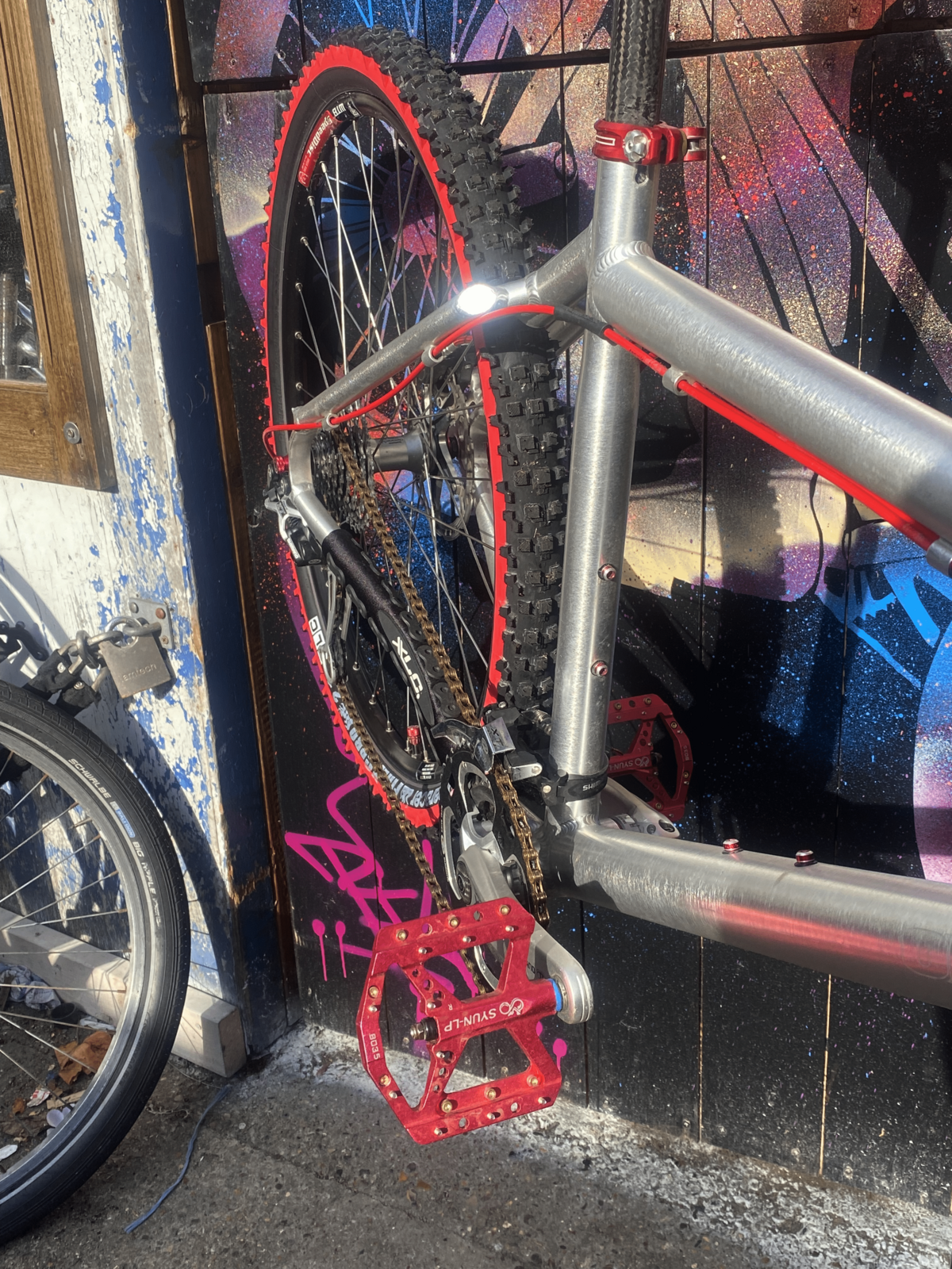 A customised bike with red pedals and golden details.